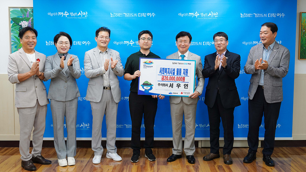 여수시장에서 사회복지시설에 물품을 지원하는 후원증서를 전달하는 장면으로, 왼쪽에는 서우인 대표가 서 있고 오른쪽에는 여수시장이 서 있다.