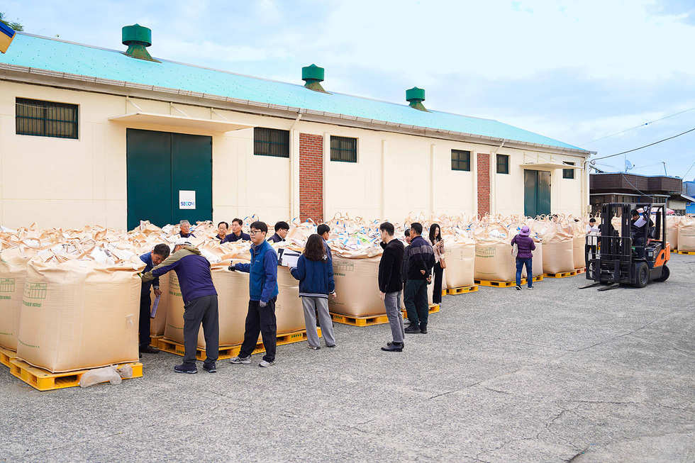 여수시 공공비축미 매입 현장에서 관계자들이 포대벼를 검사하고 지게차로 대형 톤백을 옮기고 있는 모습