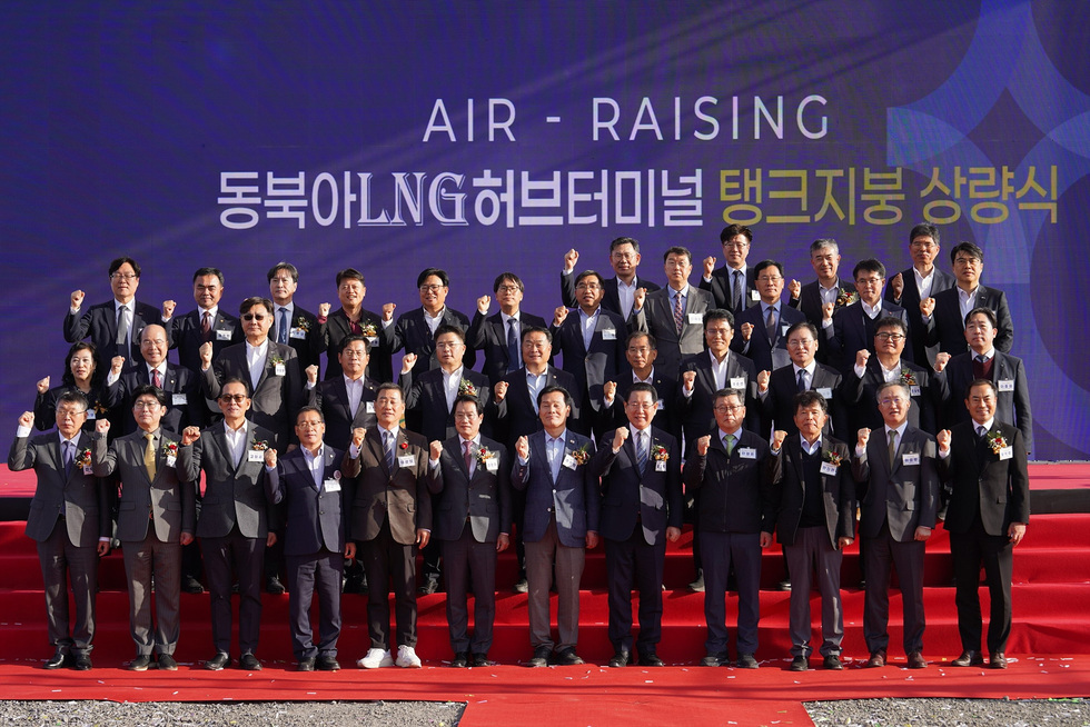 ‘동북아LNG허브터미널 탱크지붕 상량식’ 행사에서 참석자들이 붉은 단상 위에서 단체 기념사진을 찍으며 파이팅 포즈를 취하고 있는 모습
