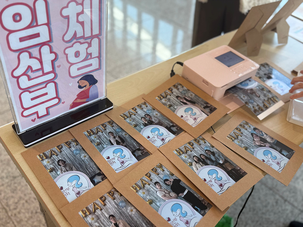 산부 체험부스’ 안내판 옆 테이블에 임산부의 날 기념 포토존에서 촬영한 사진들이 인화되어 전시된 모습