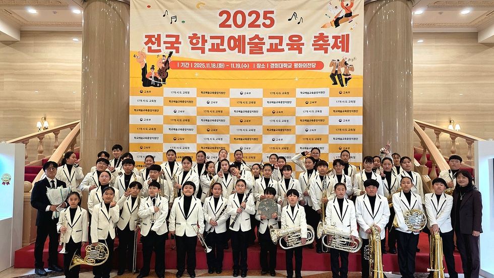 2025 전국 학교예술교육 축제 현장에서 여수청소년윈드오케스트라 단원 90여 명이 무대 배경 앞에서 단체로 기념 촬영하고 있는 모습