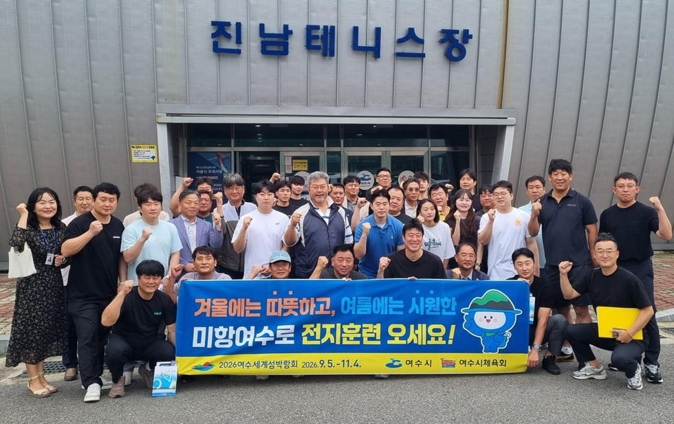 진남테니스장 앞에서 전지훈련 유치 관련 현수막을 들고 단체 기념촬영을 하는 여수시 관계자와 선수단. 모두 주먹을 들어 올리며 파이팅을 외치는 모습