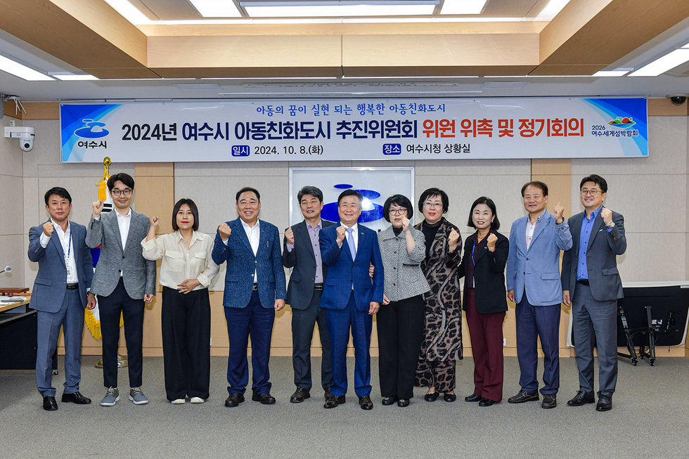 여수시청 상황실에서 2024년 아동친화도시 추진위원회 위원 위촉식이 진행되고 있으며, 여러 명의 위원들이 함께 포즈를 취하고 있다.