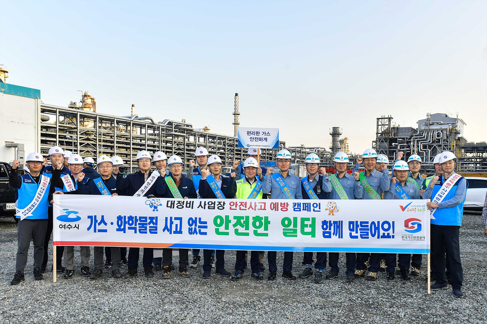 여수시에서 대정비 사업장 안전사고 예방 캠페인을 진행하는 모습으로, 여러 명의 직원들이 안전모를 착용하고 현수막을 들고 있다.