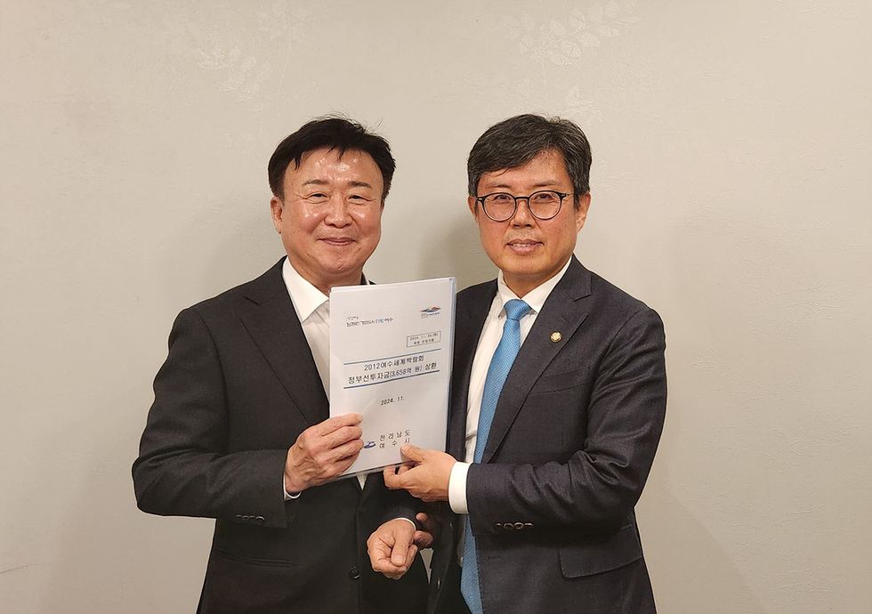 두 남성이 신재생에너지 정부세제개편안 관련 문서를 들고 기념사진을 찍고 있다.