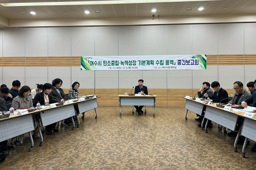 여수시에서 탄소중립과 녹색성장 기본계획 수립을 위한 중간보고회가 진행되고 있으며, 여러 참석자들이 회의 테이블에 앉아 있다.