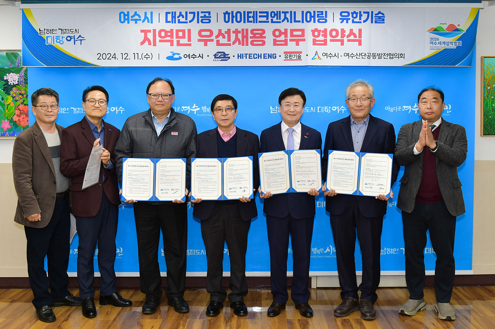 여수시에서 지역민 우선채용 업무 협약식을 체결하는 장면으로, 여러 관계자들이 협약서를 들고 서 있다.