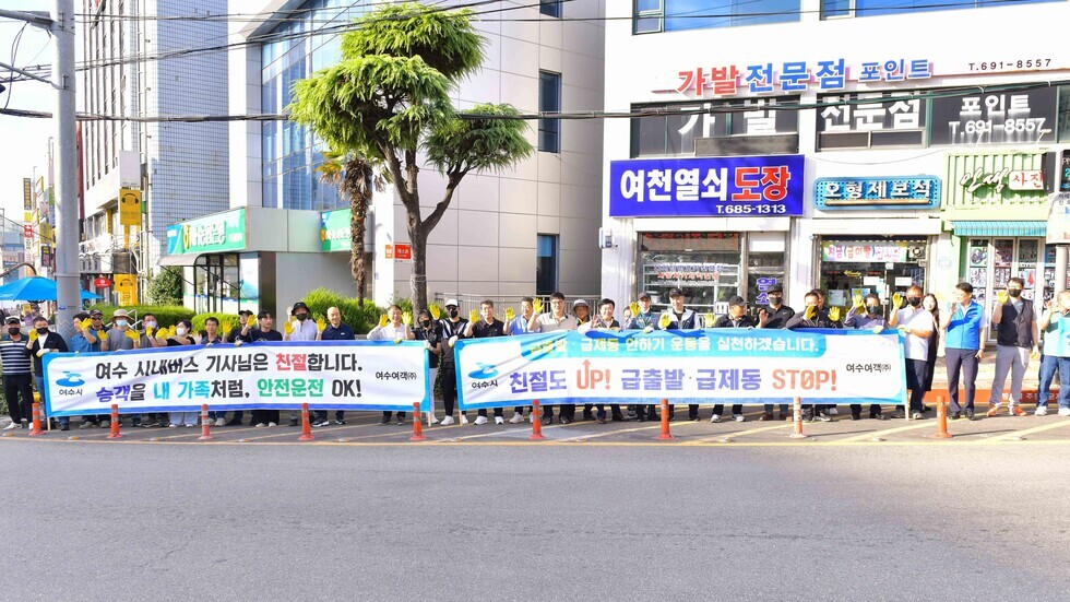 여수 시내버스 기사들이 안전운전과 친절을 강조하며 플래카드를 들고 있는 모습이다.