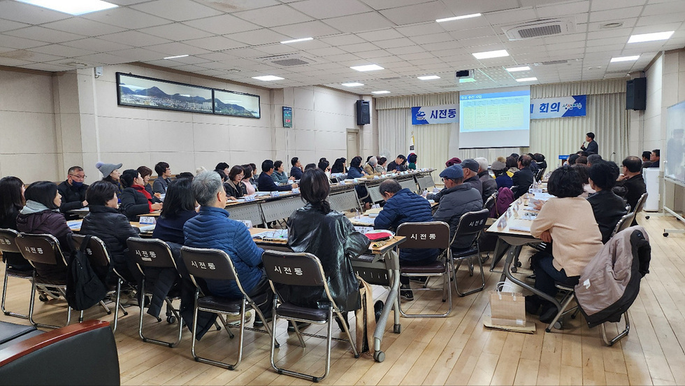 시전동에서 열린 회의에 참석한 사람들이 테이블에 앉아 발표를 듣고 있다. 화면에는 회의 내용이 표시되고 있다.