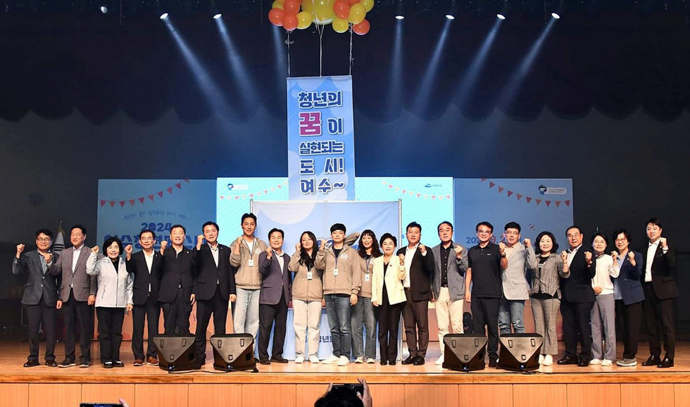 여수에서 열린 2022 청년정책 박람회에서 여러 사람들이 모여 포즈를 취하고 있다. 배경에는 청년의 꿈을 실현하자는 메시지가 적힌 현수막이 걸려 있다.