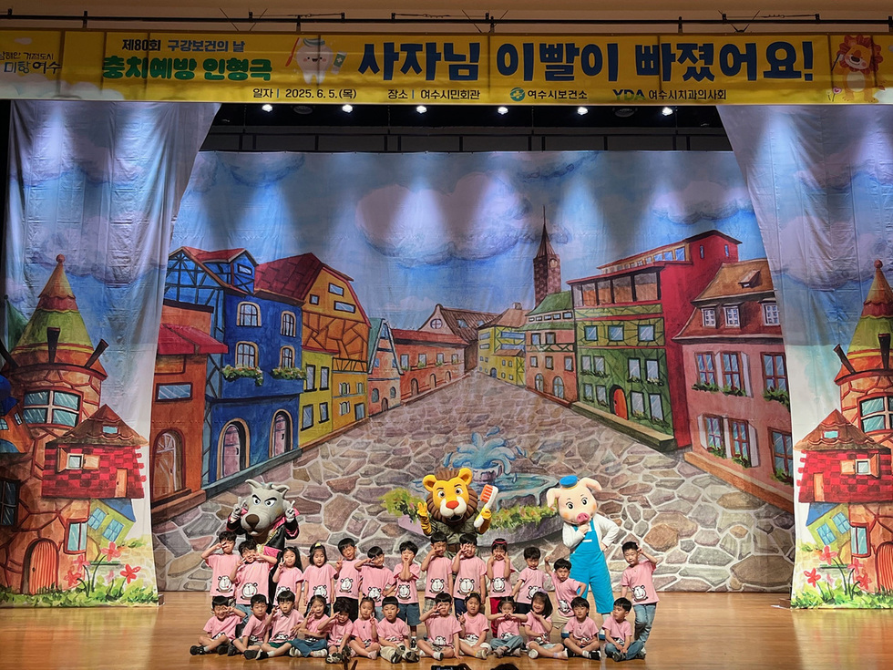 여수 시민회관에서 열린 충치 예방 인형극에서 아이들이 사자, 호랑이, 코끼리 인형과 함께 포즈를 취하고 있다.