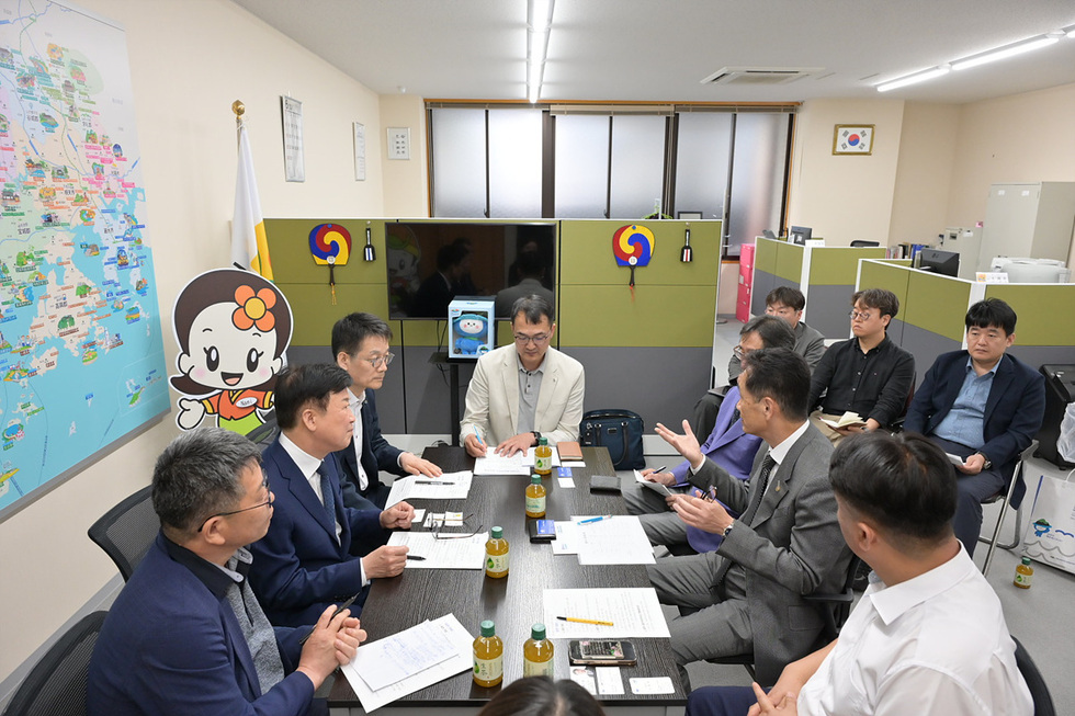 회의실에서 여러 사람이 모여 논의하고 있는 장면으로, 벽에는 한국 지도와 캐릭터가 보인다.