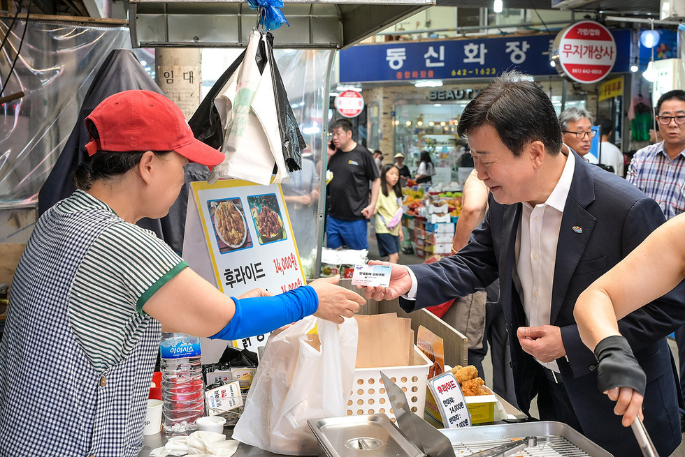 한 남성이 음식 노점에서 판매원에게 돈을 주며 후라이드를 구매하는 장면이다.