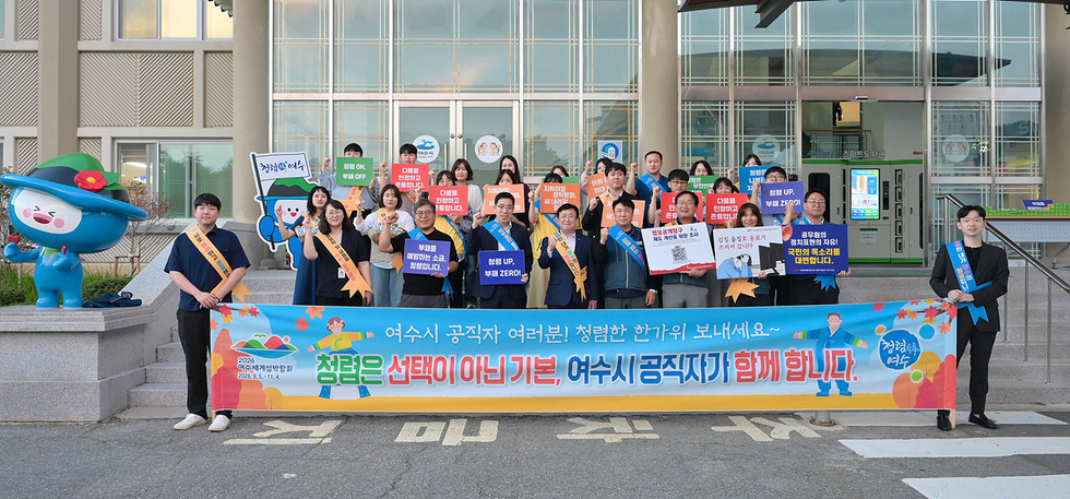 여수시 진남체육관에서 제29회 노인의 날 기념행사를 위해 모인 900여 명의 어르신과 내빈들이 여수시 공직자 여러분 청렴한 한가위 보내세요 청렴은 선택이 아닌 기본, 여수시 공직자가 함계합니다.현수막 앞에 서 있다.