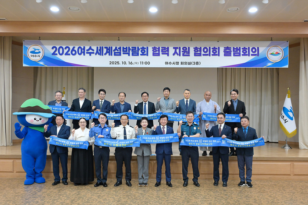 여수시청 회의실에서 2026여수세계섬박람회 협력 지원 협의회 출범회의가 열리고 있으며, 참석자들이 손을 들어 포즈를 취하고 있다.