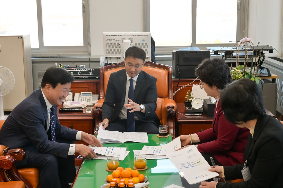 정기명 여수시장이 사무실 내 회의 테이블에서 관계자들과 함께 2026년도 정부 예산 자료를 검토하며 대화를 나누는 모습이다. 네 사람이 테이블 둘레에 앉아 자료를 펼쳐 보며 의논하고 있다,